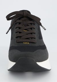Chaussure de sport noire avec un haut texturé, des sections en mesh contrastantes, un design à lacets et une semelle blanche à forme courbée.