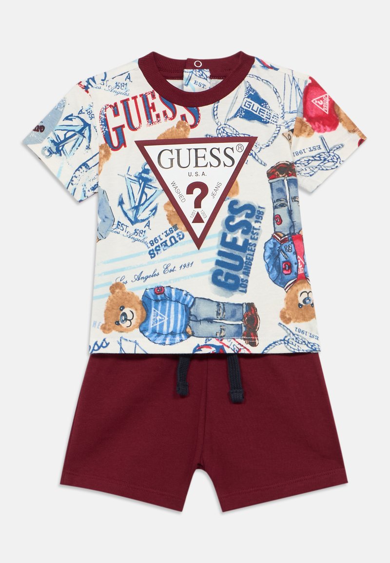 Μπλουζάκι με πολύχρωμη εκτύπωση αρκούδας και κειμένου, κόκκινο τριγωνικό λογότυπο· σετ με κόκκινα σορτς με ελαστική μέση και κορδόνι.