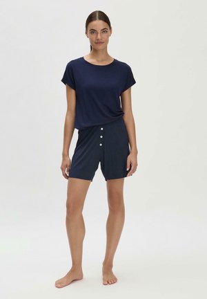 Navy t-shirt in soft fabric with rolled sleeves, paired with navy shorts featuring a button front. The shorts have a relaxed fit and no visible patterns.