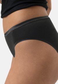 Slip in cotone nero con una texture liscia e un ampio elastico in vita. Il design presenta un taglio classico senza motivi visibili.