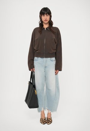 Hnedá skrátená bunda na zips, svetlomodré roztrhané široké rifle, leoparďové mules a čierna taška na rameno so zlatými detailmi.