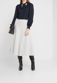 Námornícky top s detailem na zavazování a nabíranými rukávy, kombinovaný se světle šedou áčkovou sukní a černými kozačkami po kolena. Černá kabelka na ruku.