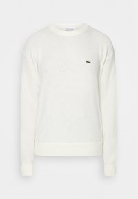 White crewneck sweater made of soft fabric. Features ribbed cuffs and hem. Small green Lacoste logo on the chest. Simple, classic design.