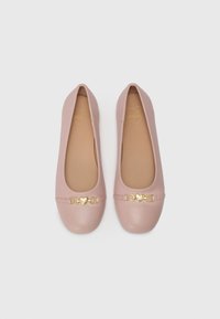 Sapatilhas de ballet em rosa pálido com biqueira arredondada e um detalhe de fivela em forma de coração dourado na parte frontal. Material suave e design minimalista.