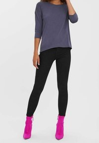 Dark gray three-quarter sleeve top paired with black leggings. Model wears bright pink ankle boots with a zip detail. Smooth fabric texture.