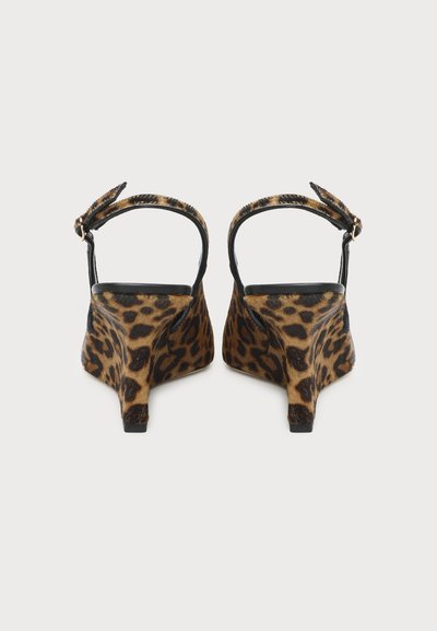 Paire d’escarpins slingback à motif léopard, brides à la cheville et petits talons compensés, vus de dos sur fond blanc.