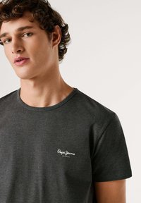 Siva kratka majica s kratkimi rokavi iz mehkega bombaža z okroglim izrezom in majhnim belim logotipom na zgornjem levem delu prsnega koša.