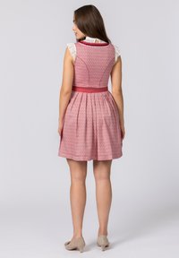 Rotes Kleid mit gemustertem Stoff, Spitzenärmeln, tailliertem Oberteil und weit ausgestellt Rock, akzentuiert durch einen breiten Gürtel aus Satin.