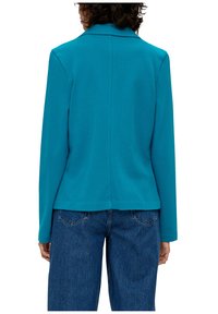 Turkusowa marynarka z klapami, długimi rękawami i prostym krojem, zestawiona z niebieskimi spodniami typu wide-leg. Gładka faktura, brak widocznych wzorów.