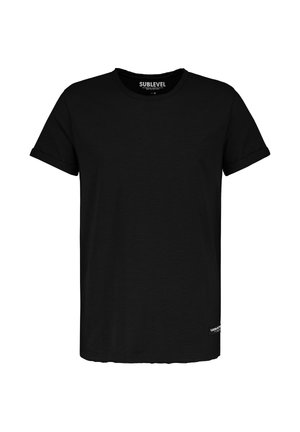 Schwarzes T-Shirt mit kurzem Arm und Rundhalsausschnitt, mit aufgekrempelten Manschetten und einem kleinen weißen "Urban"-Label nahe dem unteren Saum auf der linken Seite.
