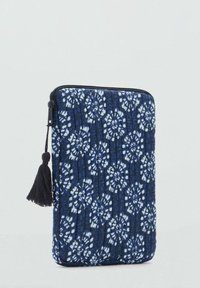 Housse de tablette matelassée bleu marine avec motif floral blanc, fermeture zippée et accent en gland noir. Surface texturée pour une meilleure prise.