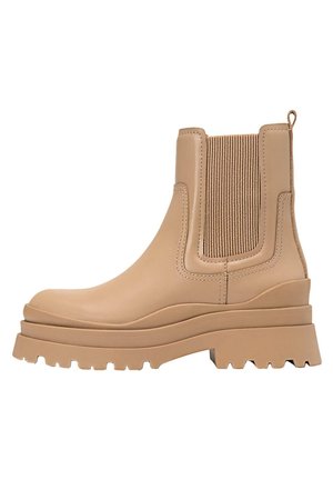 Bottes chevilles beiges en cuir lisse, avec des panneaux élastiques sur les côtés et une semelle épaisse et robuste pour une meilleure adhérence.