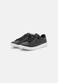 Sneaker in pelle nera con suola in gomma bianca, punta rotonda, design classico con lacci e dettagli di cucitura discreti.