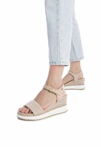 Sandali con tacco a cuneo beige con texture intrecciata e cinturino alla caviglia regolabile. Sole leggero con una sottile piattaforma rialzata e base bianca.