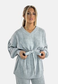 Maglione grigio lavorato a maglia con scollo a V, caratterizzato da righe verticali, maniche oversized e una cintura annodata in vita. Tessuto strutturato.