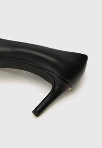Black high-heeled shoe made of smooth leather, featuring a pointed toe, slender heel, and subtle gold accent near the back.