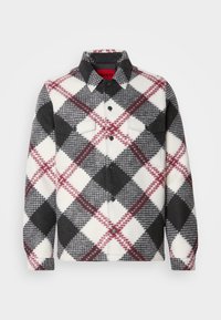 Flannel shirt in black, white, and red plaid, featuring a collar, two chest pockets, and long sleeves with button cuffs.