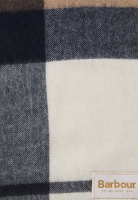 Tessuto in morbida lana con un grande motivo a quadri nero, grigio e crema, con etichetta del marchio Barbour nell'angolo in basso a destra.