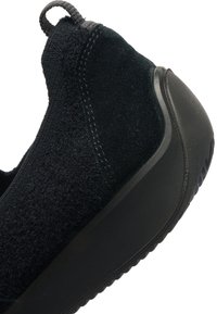 Schwarze Sneaker mit strukturiertem Obermaterial, glatter Gummisohle und einer Schlaufe an der Ferse für ein einfaches Anziehen.