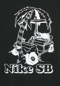Czarna koszulka z białą grafiką przedstawiającą wózek golfowy pod palmą, z napisem "Nike SB" poniżej. Proste linie i wyraźne kontrasty.