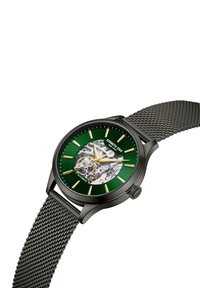 Automatische Uhr mit schwarzem Metall-Mesh-Armband. Das grüne Zifferblatt hat goldene Stundenmarkierungen und einen transparenten Abschnitt, der die komplexe Mechanik zeigt.