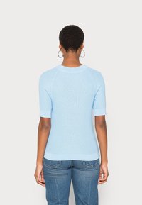 Jasnoniebieski prążkowany krótki top z dzianiny z okrągłym dekoltem i dopasowanym fasonem; posiada kontrastujące mankiety i dół.