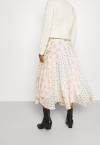 Blomsterpræget midi-nederdel med asymmetrisk søm, lavet af let stof. Har rosa og blå blomster mod en hvid baggrund.
