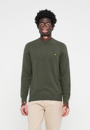 Pull en tricot vert avec un col rond et des manches longues. Présente un petit logo jaune sur la poitrine. Texture douce et coupe ajustée.