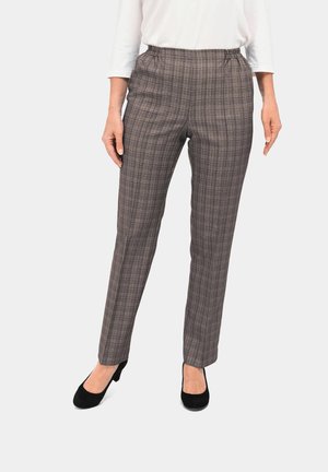 Pantalons à carreaux avec taille élastique dans des teintes de marron et de beige, présentant une coupe ajustée. Portés avec des talons noirs, associés à un top blanc.