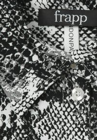 Nahaufnahme eines schwarz-weißen Schlangenhautmuster-Hemdkragens mit weißen Knöpfen und Etiketten, die "frapp" und "DONPA" lesen.