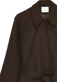 Hnedý vlnený kabát s širokým golierom, s opaskom na viazanie v páse a štruktúrovaným povrchom. Dizajn zdôrazňuje štruktúrovanú siluetu.
