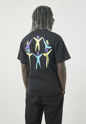 Black cotton t-shirt featuring a colorful graphic on the back, depicting abstract figures in yellow, purple, and blue against the fabric.