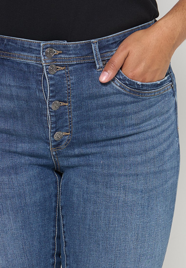 Hochgeschnittene blaue Jeans aus Denim mit einem Schließsystem aus vier Knöpfen, vorderen Taschen und einer schmalen Passform mit sichtbaren Steppnähten.
