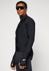 Black athletic long-sleeve jacket with a high collar, paired with fingerless black gloves. Smooth texture and fitted design.