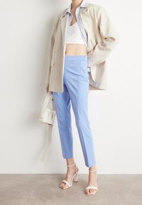Beige oversized blazer, white crop top, light blue tailored pants, and white block-heeled sandals. Accessories include a small white bag.