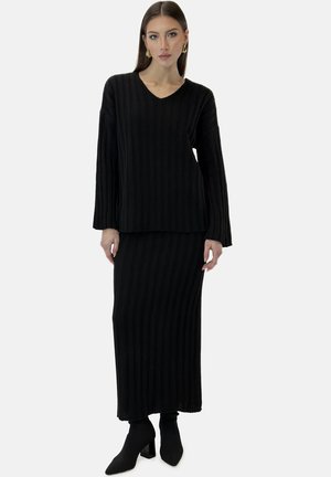 Schwarzes, gerippte Strick-Zweiteiler-Outfit mit einem Langarmoberteil mit V-Ausschnitt und einem passenden knöchellangen Rock, kombiniert mit schwarzen High-Heel-Stiefeln.
