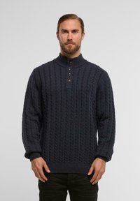 Dziergany granatowy sweter z wysokim kołnierzem, listwą z czterema guzikami oraz teksturowanym wzorem w warkocze; ściągacze przy mankietach i na dole.