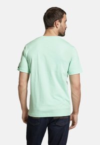 Tricou din bumbac verde mentă, cu mâneci scurte, decolteu rotund și croială lejeră, expus din spate pe un fundal alb.