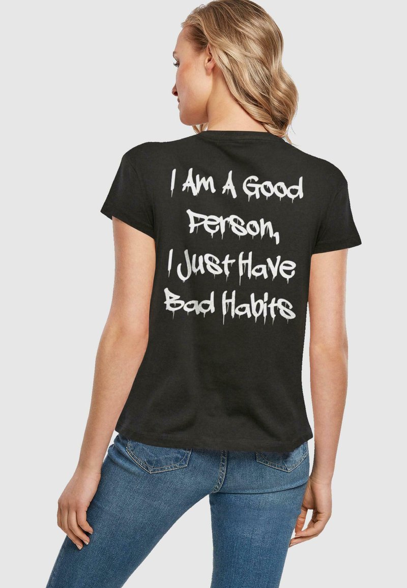 Sort kortærmet t-shirt med hvid graffiti-lignende tekst på ryggen, der står: "Jeg er en god person, jeg har bare dårlige vaner."