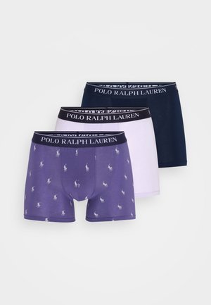 Tre par med herreboxershorts i lilla med mønstre, hvit og marineblå. Hver av dem har en svart linning med "POLO RALPH LAUREN"-logo.