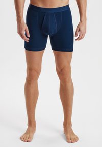 Marineblå boxershorts lavet af blødt stof, med en tætsiddende pasform, elastisk talje og en forstærket frontlomme.