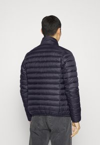 Granatowa kurtka puchowa z poziomymi przeszyciami, wysokim kołnierzem i gładką fakturą, z dopasowanym fasonem i elastycznymi mankietami.