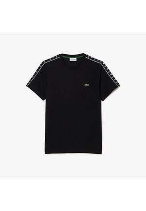 Schwarzes T-Shirt mit kurzen Ärmeln und Rundhalsausschnitt, weißem „Lacoste“-Schriftzug auf den Schulterstreifen und kleinem grünen Krokodil-Logo auf der linken Brust.