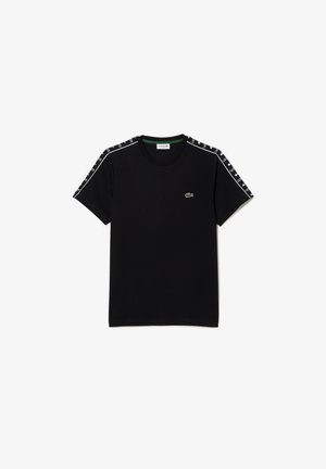 Schwarzes T-Shirt mit kurzen Ärmeln und Rundhalsausschnitt, weißem „Lacoste“-Schriftzug auf den Schulterstreifen und kleinem grünen Krokodil-Logo auf der linken Brust.