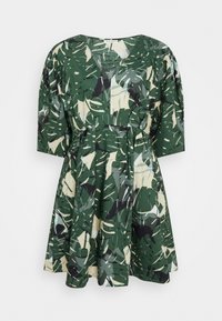Robe à motifs verts présentant des feuilles tropicales en vert foncé, vert clair, noir et beige, avec un décolleté en V, des manches courtes bouffantes et une jupe évasée.
