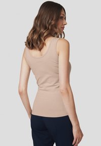 Beżowy top na ramiączkach wykonany z miękkiego, elastycznego materiału; dopasowany krój z szerokimi ramiączkami i okrągłym dekoltem.