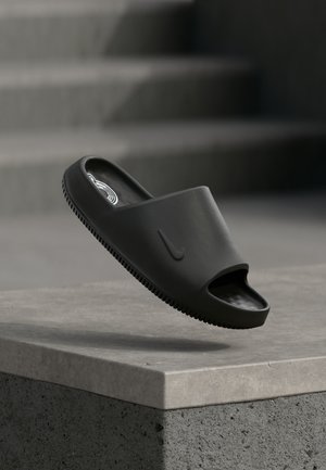 Μαύρη σανδάλι τύπου slide, κατασκευασμένη από λείο καουτσούκ. Σχεδιασμός με ανοιχτά δάχτυλα, με λογότυπο στο πλάι και υφή στην σόλα για καλύτερη πρόσφυση. Ελαφριά και μινιμαλιστική μορφή.