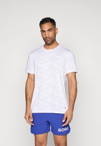 Hvid camouflaged t-shirt med rund halsudskæring, korte ærmer og emblemdetalje. Sættes sammen med blå shorts med hvid "BORG" branding.