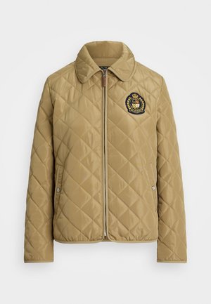 Giacca trapuntata beige con colletto, zip frontale, tasche laterali e un emblema ricamato con una corona e una corona d'alloro sul lato sinistro del petto.