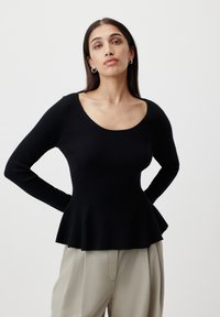 Black ribbed sweater with long sleeves and a scoop neck, featuring a flared hemline and textured pattern. Model-style presented.